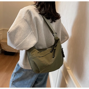 Detail of army green nylon hobo bag showing the waterproof fabric and woven rope zipper pull