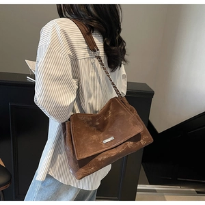 Detail view of deep brown vintage leather shoulder bag with silver chain and metal logo