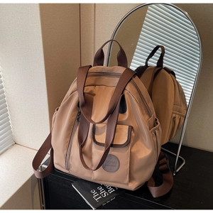 Detail view of khaki nylon backpack with brown straps and SD&N logo on front