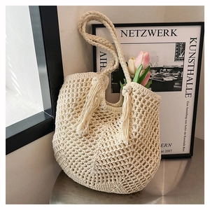 Detail of cream handmade crochet tote bag with fringe accents and woven shoulder strap