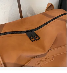Detail of smooth double zipper and brand embossing on brown frosted tote bag