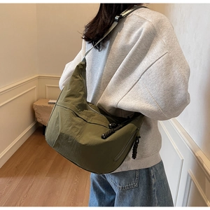 Detail of army green nylon hobo bag featuring wide strap and braided zipper pull