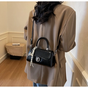 Black glossy crossbody bag with silver twist lock and decorative silk scarf detail