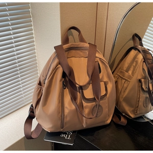 Detail of a large khaki oxford backpack with multiple pockets and soft natural window light