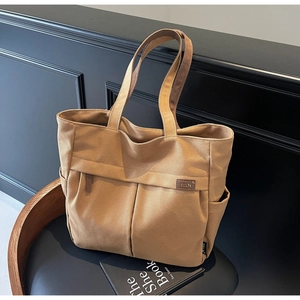 Close-up of khaki canvas tote bag featuring double front pockets and leather TELN logo