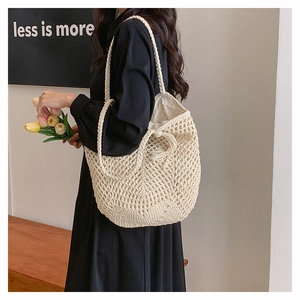 Detail of cream woven tote bag with fringe tassels and inner lining on a wooden bench