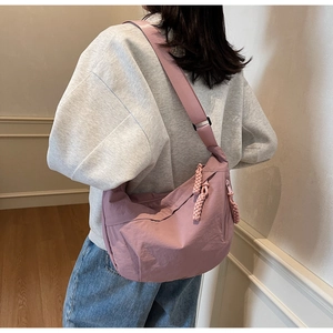 Pink nylon crescent shoulder bag shown on model with woven rope zipper detail