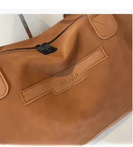 Close-up of NINGJIA embossed leather detail and durable black metal double zipper on tote bag