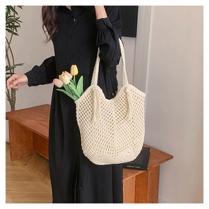 Detail of hand-woven crochet tote bag featuring fringe tassels and elegant mesh texture