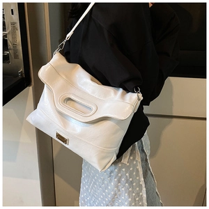 Detail of white large bucket bag with shiny leather texture and decorative cutout handle