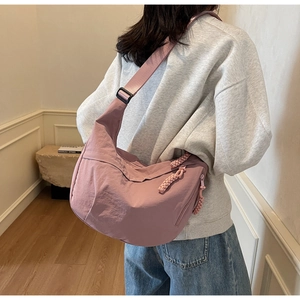 Detail of dusty pink nylon crescent bag with woven zipper pull and adjustable strap