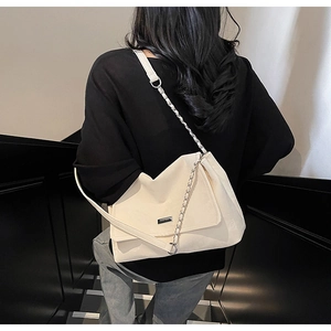 Close-up of a cream-white tote bag featuring a silver chain strap and metal logo plate