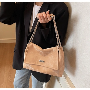 Close-up of beige suede tote bag with double chain straps on model in casual suit