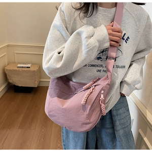Detail of dusty rose nylon crescent bag with woven zipper pulls and wide strap