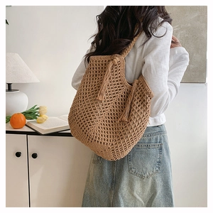 Detailed close-up of bohemian woven tote bag with fringe tassels and mesh pattern