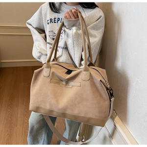Detail of khaki tote bag showing long handles, detachable strap and brand logo engraving