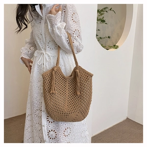 Detail of hand-woven crochet tote bag with fringe tassels in earthy brown color