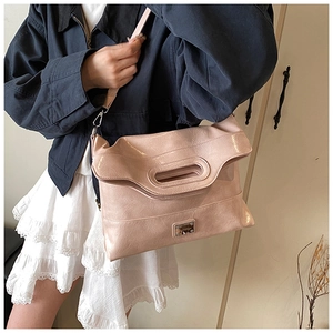 Detail of light pink crossbody bucket bag with square metal lock and litchi texture leather