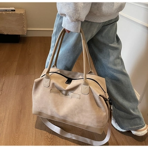 Détail d'un grand sac fourre-tout beige avec zips noirs et bandoulière réglable