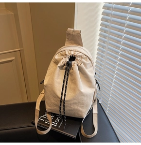 Vue détaillée du sac seau en toile beige avec fermeture à cordon et bandoulière tissée