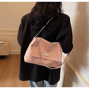 Detailed macro of pink suede leather shoulder bag with chic silver logo and metal chain strap
