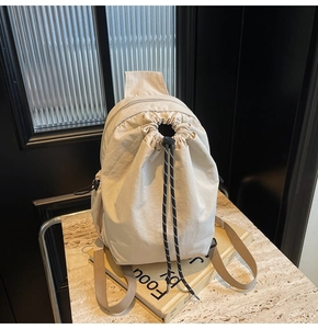 Détail du sac à dos en nylon beige à cordon, texture plissée et détails de corde contrastée