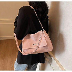 Détail du sac cabas en daim rose avec chaîne métallique et bandoulière sur l'épaule