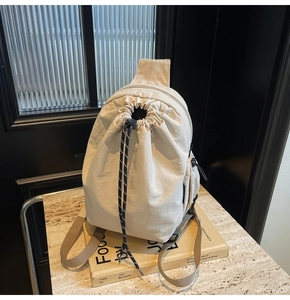 Détail d'un sac à dos en toile beige avec fermeture à cordon et fermeture éclair latérale