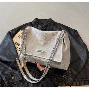 Detail of silver chain strap and metal logo on a vintage textured shoulder bag