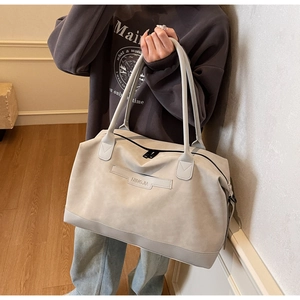 Detail view of large grey suede tote bag with zip closure and minimalist brand patch