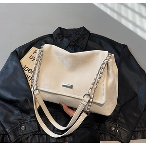 Detail of white leather shoulder bag with silver chain strap and metal logo plaque
