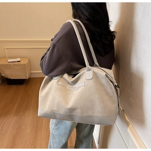 Détail du grand sac cabas gris clair avec logo embossé et texture suédée élégante