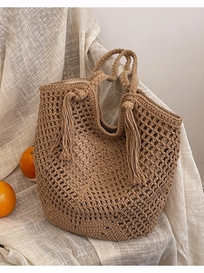 Handmade woven hollow tote bag in khaki with tassels on white textured fabric