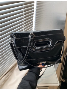 Black casual bucket bag with white contrast stitching and unique hollow handle detail