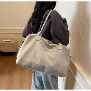 Détail d'un grand sac fourre-tout gris avec texture souple et logo MINGJIA élégant