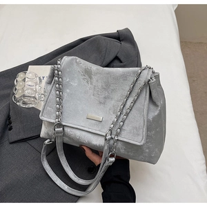 Detail of silver matte tote bag with metallic chain strap and square logo plate