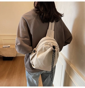 Vue arrière du sac bandoulière multifonctionnel blanc cassé sur un mannequin au style épuré