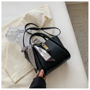 Détail du sac seau noir en cuir grainé avec foulard en soie et fermoir doré chic