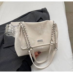 Detailed close-up of textured ivory faux leather tote bag with silver chain strap and logo