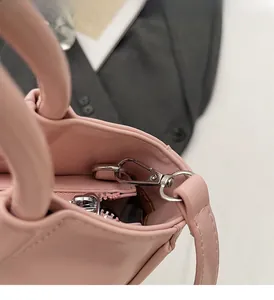 Detailed view of silver metal hooks and pink zipper on a trendy bucket bag strap