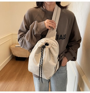 Détail du sac bandoulière en nylon beige avec cordon de serrage et large bandoulière