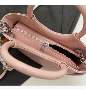 Close-up of pink PU leather bucket bag with silver zipper and colorful beaded charm