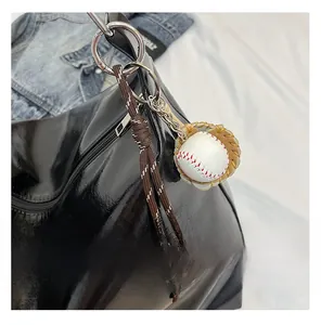 Detailed close-up of a baseball glove and ball keychain accessory on a leather bag