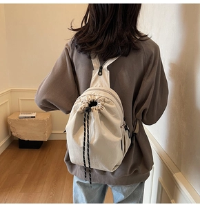 Détail du sac à dos en toile crème avec cordon de serrage et bretelles triangulaires