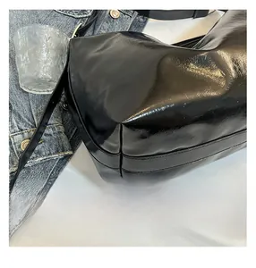 Close-up of black glossy oil wax leather bag texture with precise double stitching