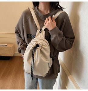 Détail du sac à dos en toile blanc cassé montrant le cordon de serrage et la texture