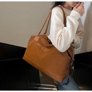 Detail of a brown large capacity tote bag with NINGJIA embossed logo and dual shoulder straps
