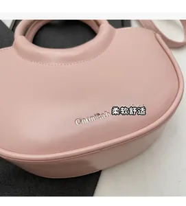 Detail of soft pink crescent bucket bag with unique round handle and sleek leather finish
