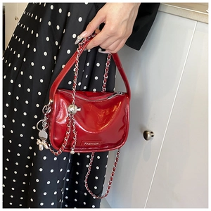Detail of red patent leather mini bag with silver chain strap and balloon dog charm