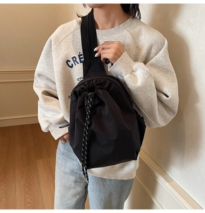 Détail du sac bandoulière en toile noire avec cordon, intérieur spacieux et large sangle